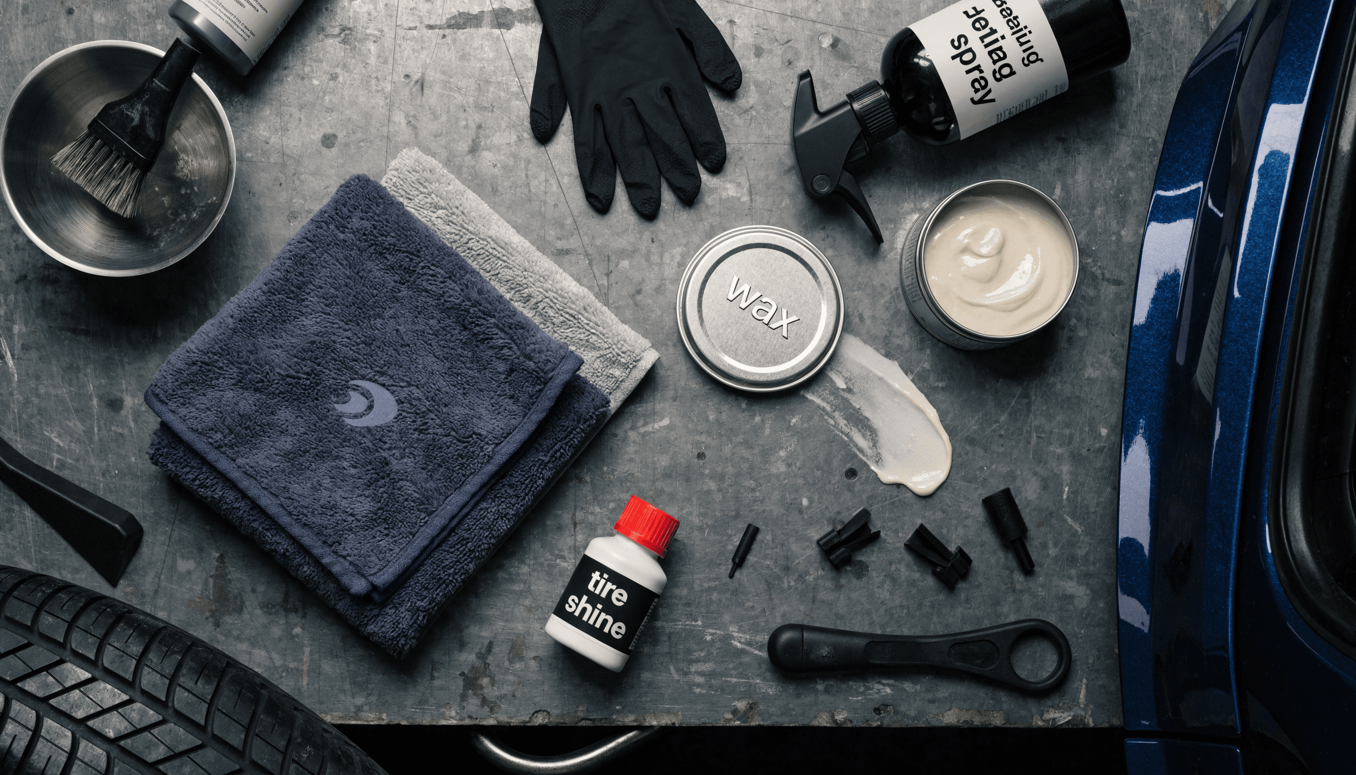 A flat lay of car detailing products on a garage workbench