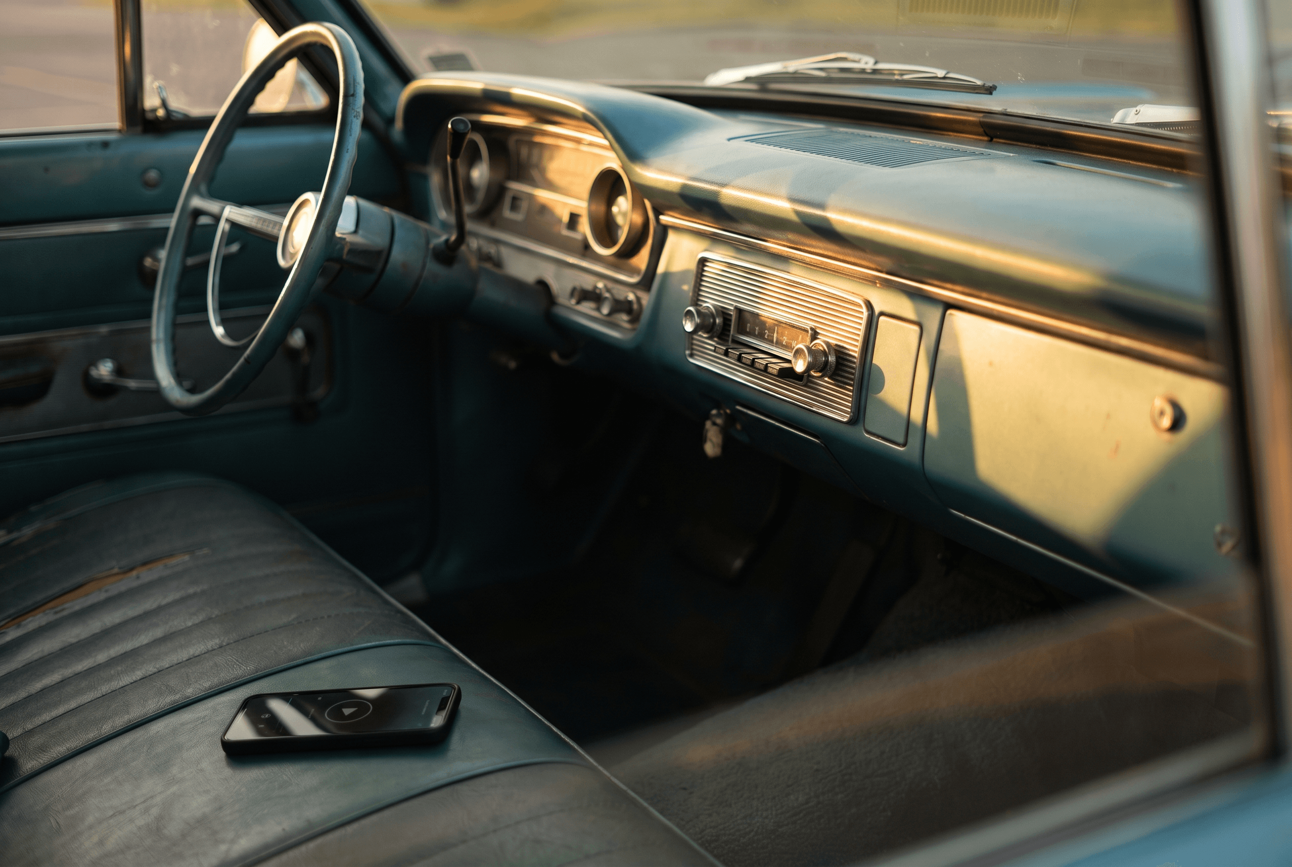 The dashboard of a classic car with its original-style radio in place, lit by soft evening light, with no modern screens visible