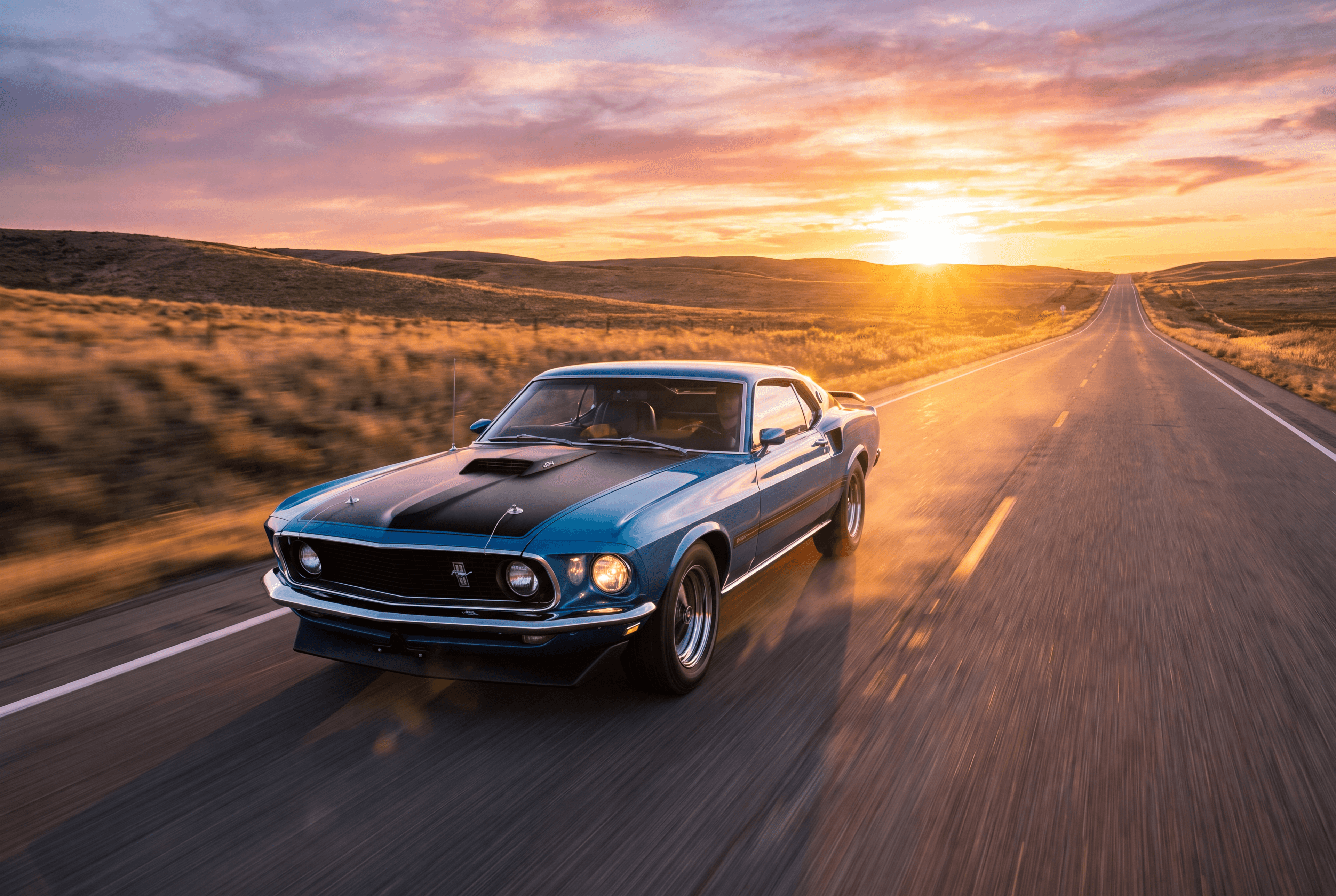 A classic car on an open highway with a scenic road stretching toward the horizon, no people visible
