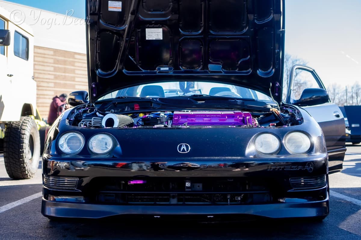 Front view of the black Integra GSR with the hood up showing the purple valve cover