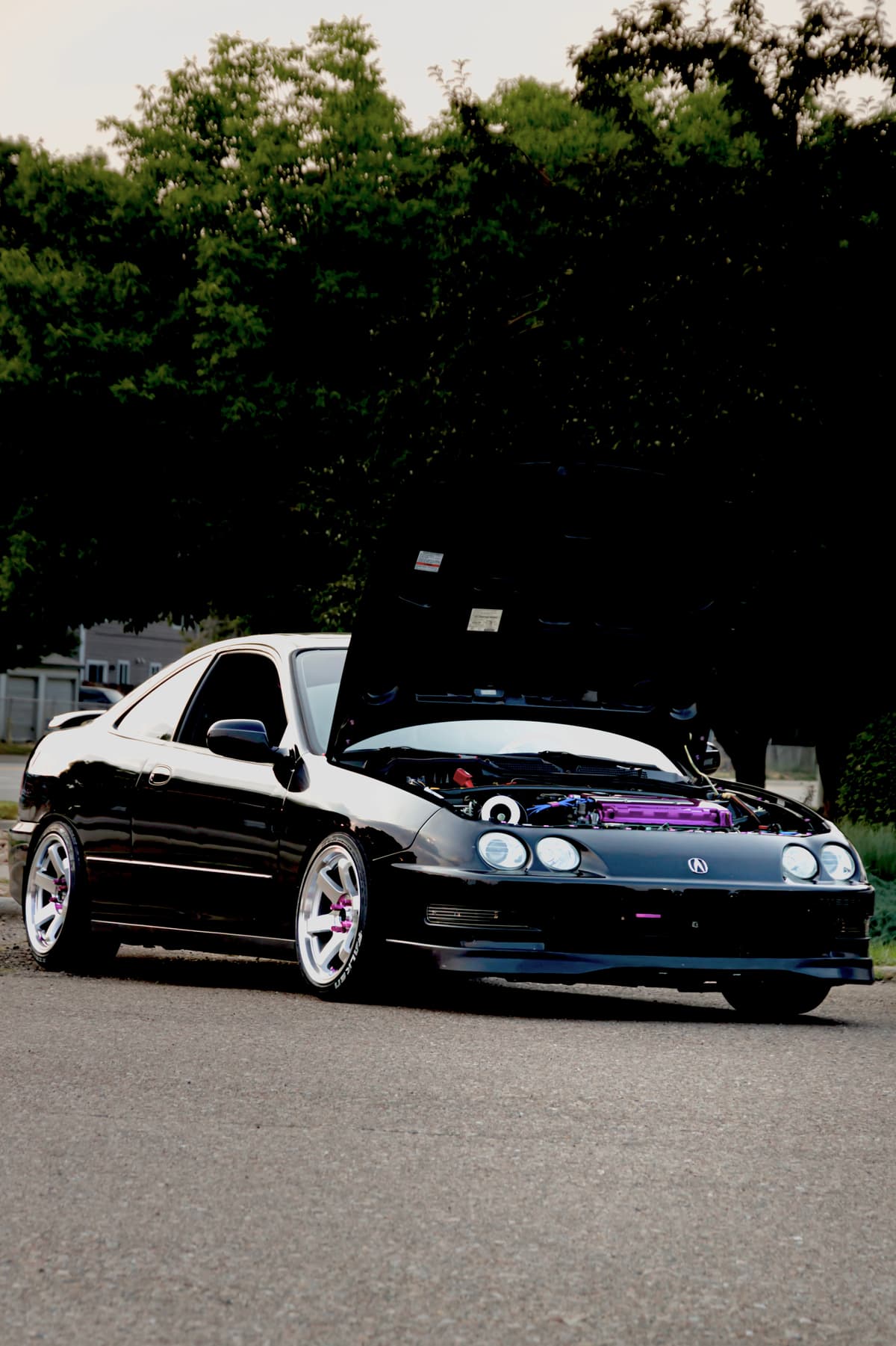 Front three-quarter view of the black pearl Integra GSR with the hood up and purple engine accents