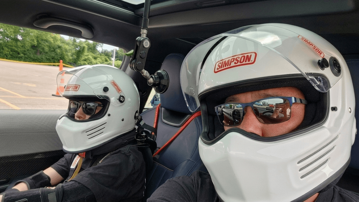 Driver and passenger in the Mini, both wearing white Simpson helmets