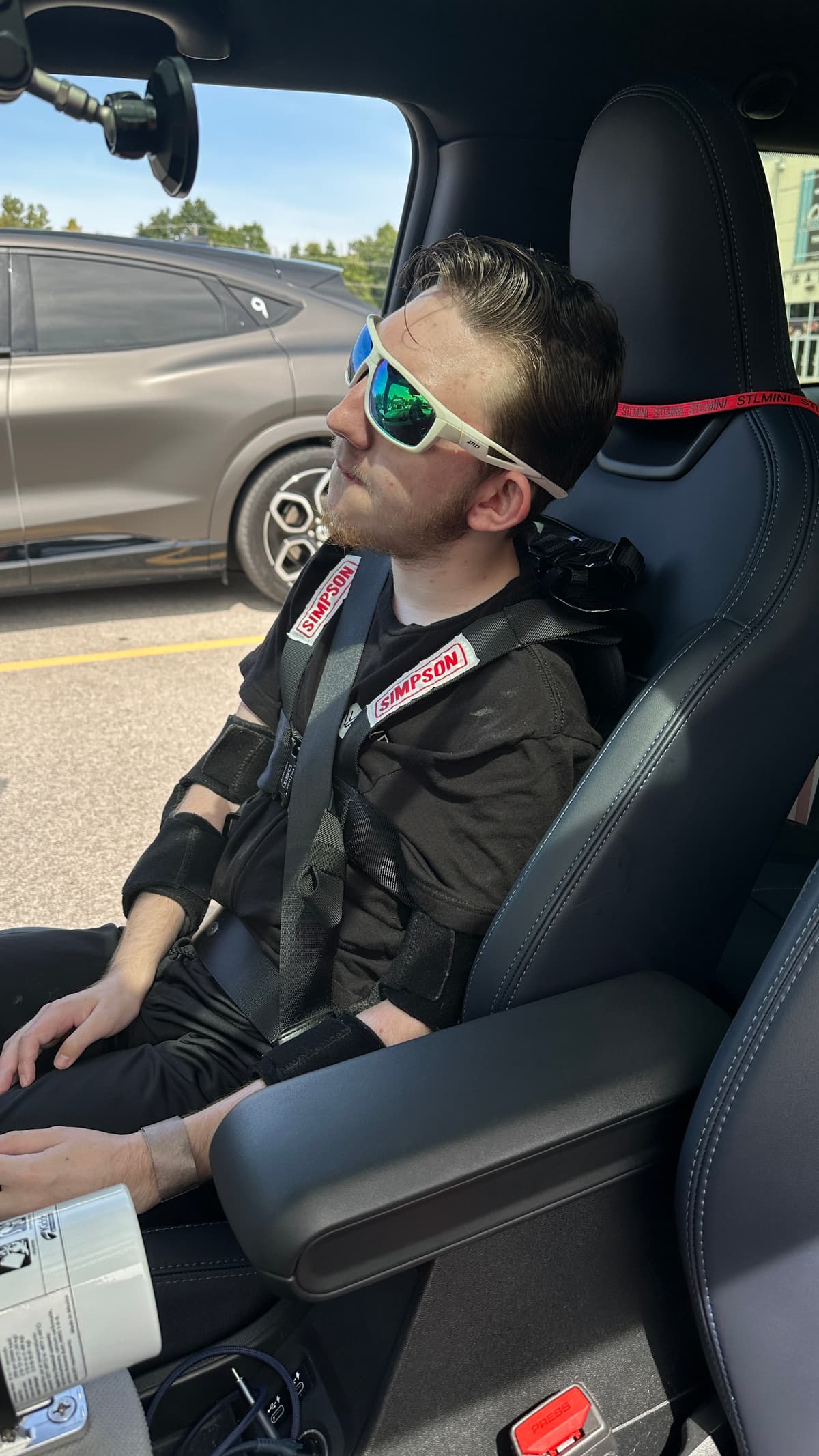 Steve's son sitting in the passenger seat in a racing jacket and sunglasses